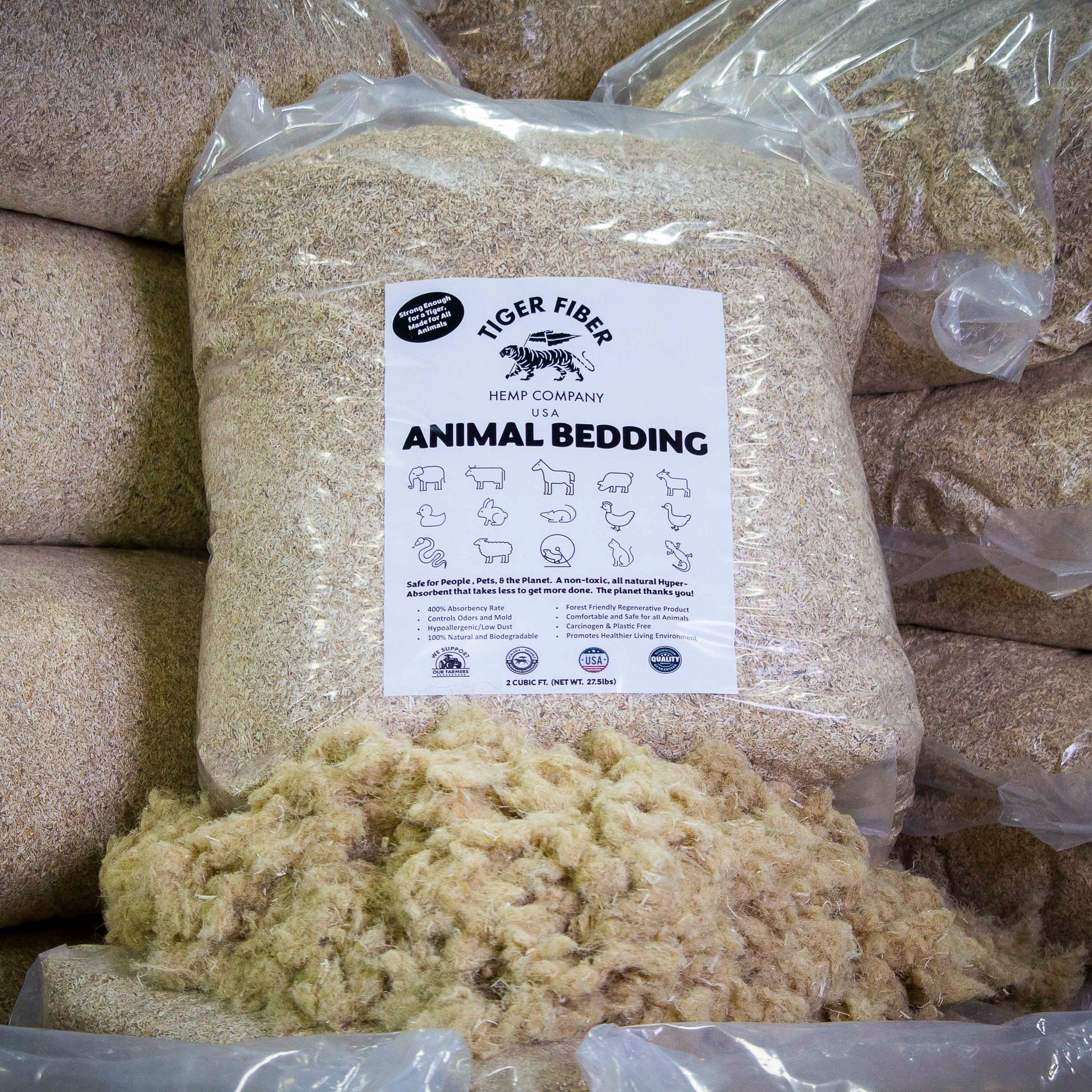 A 27.5 pound translucent packaged bag of hemp Animal Bedding sits on top of raw hemp fiber in front of stacked piles of the same product.